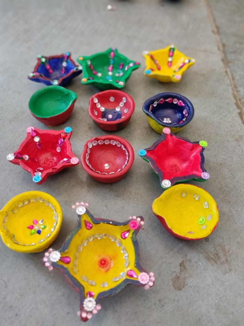 Handmade coloured/decorated diyas arranged on the floor