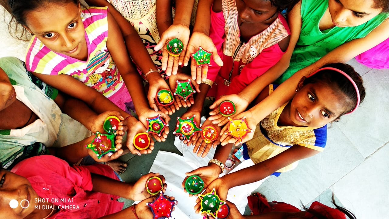 Children show the decorated diyas they have made.