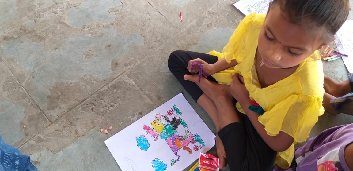 Young girl concentrating on a drawing while seated on the floor