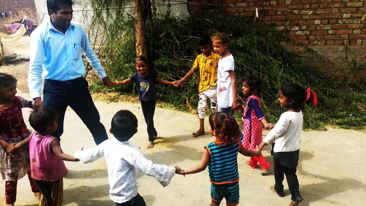 Adult and children holding hands in a large circle during an outdoor activity