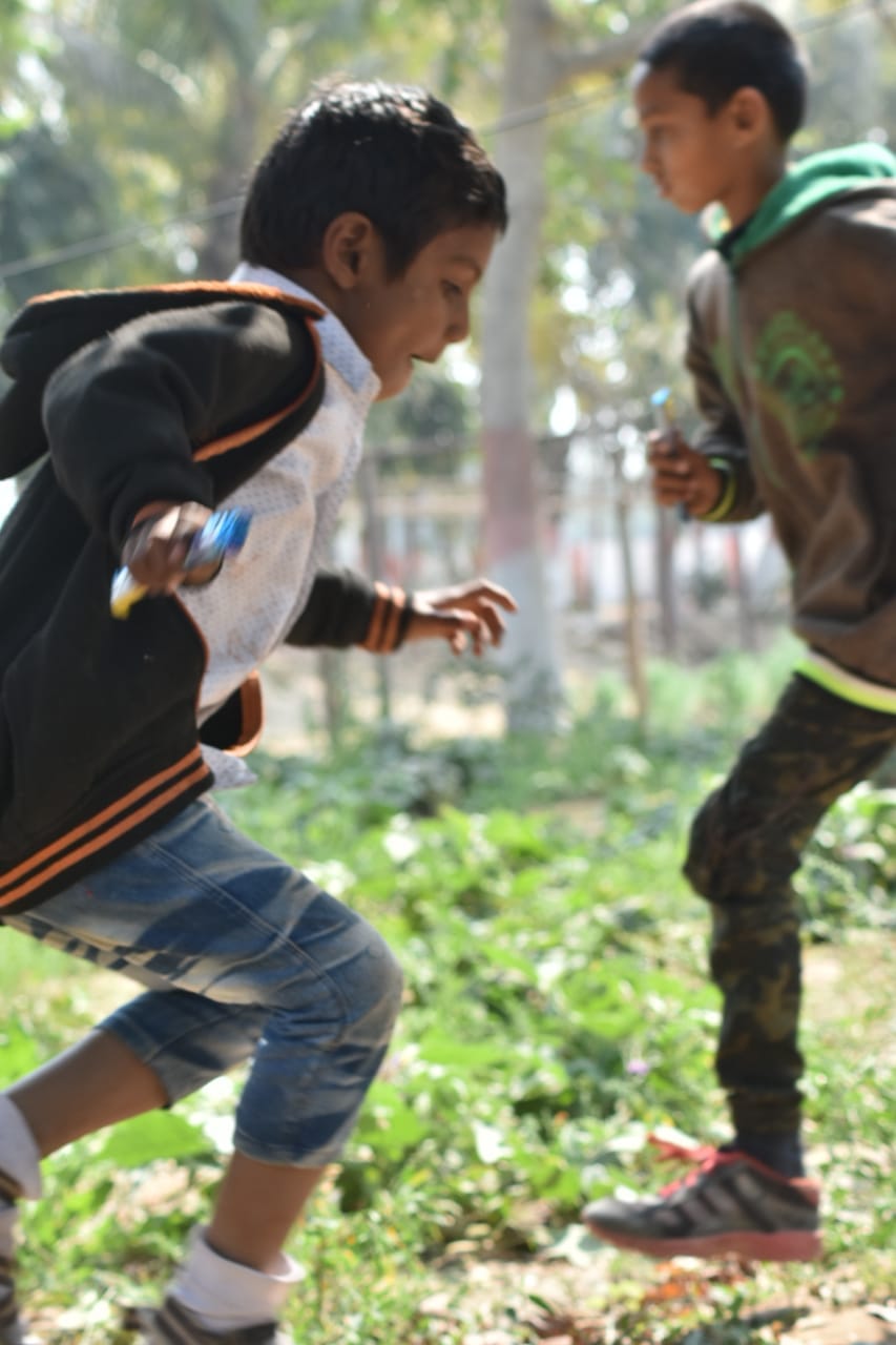 Two boys actively running/playing outdoors