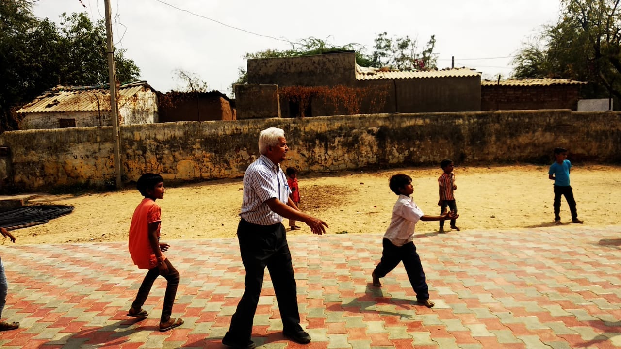An older volunteer joins children in an outdoor game.