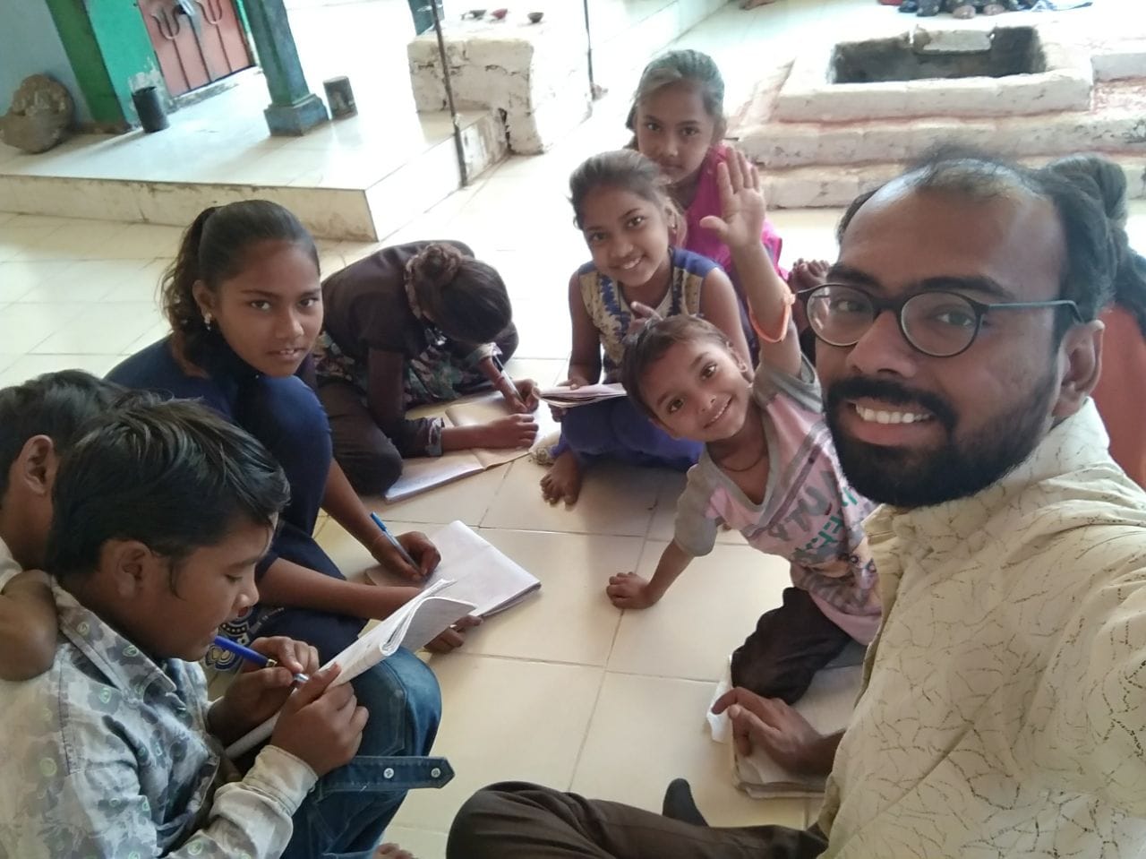 Volunteer taking a selfie with children who are simultaneously working/writing