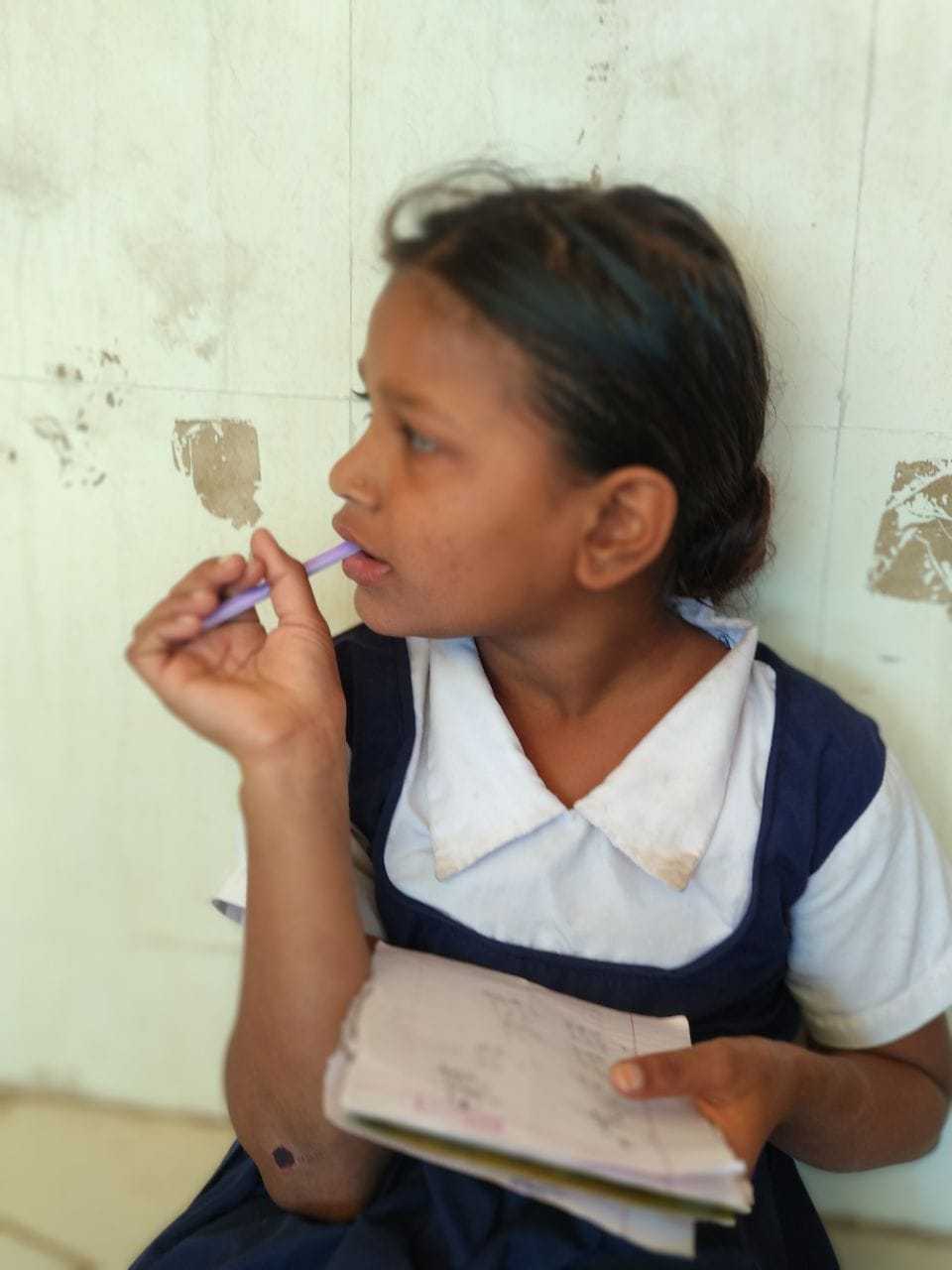 Girl in school uniform working with a notebook/pencil