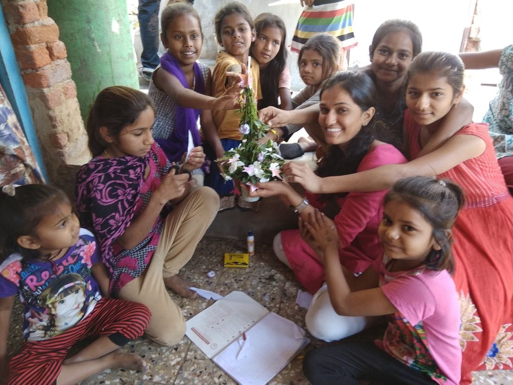 Girls and a volunteer create a decorative handmade object together.