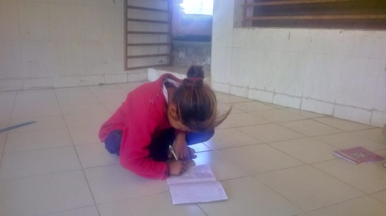 Child independently writing on notebook on the floor