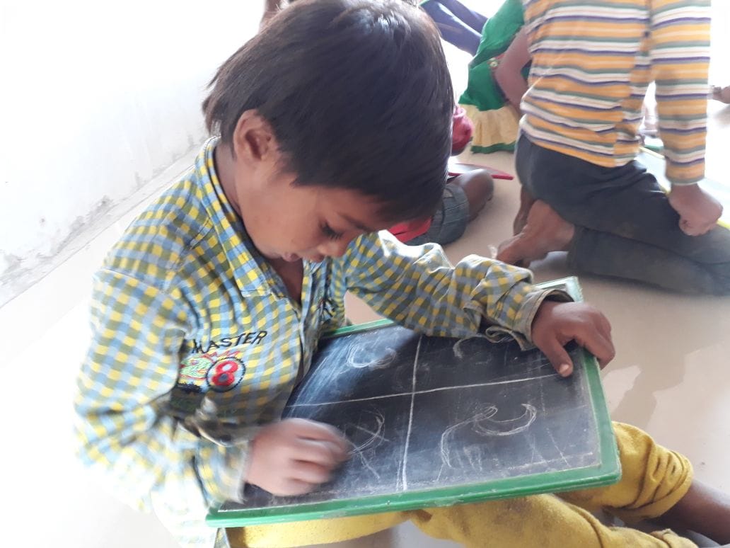 Child actively writing/drawing on slate