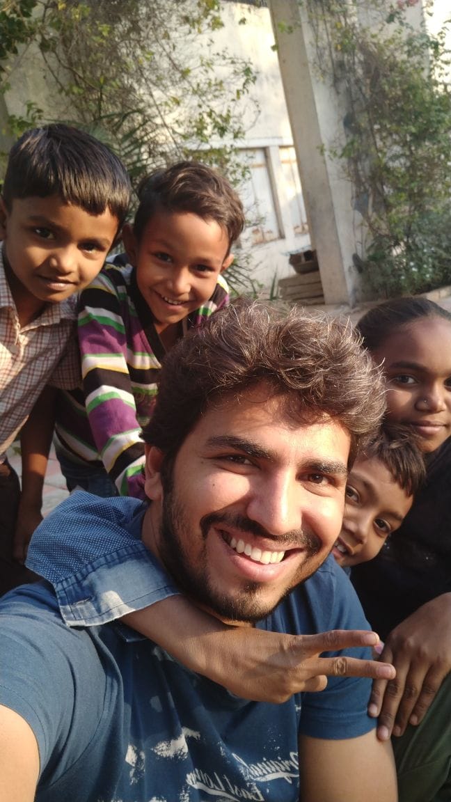 Very intimate volunteer + children selfie; children are physically close and comfortable around the volunteer