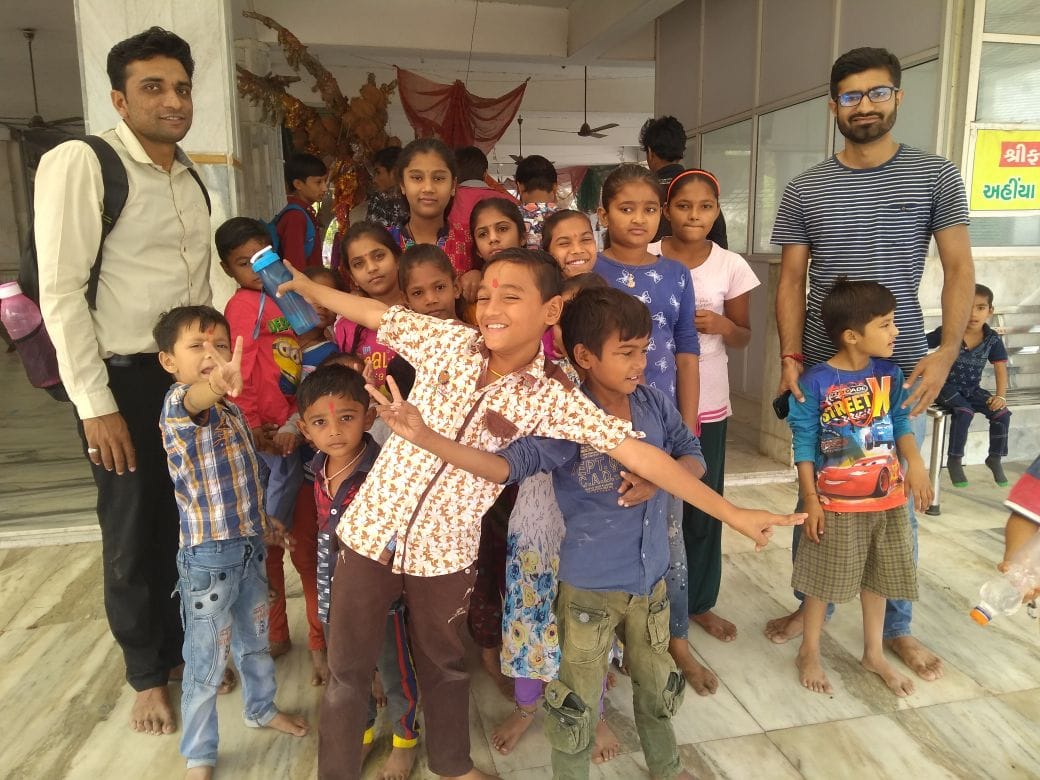 Large group of children with two adult/young volunteers in an institutional/public setting