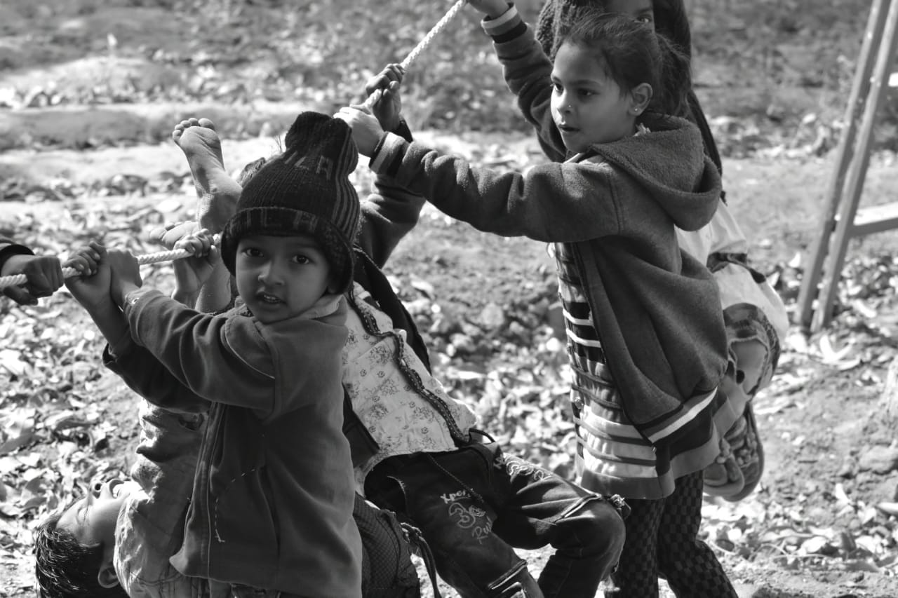 Black-and-white photograph of children playing together around a rope