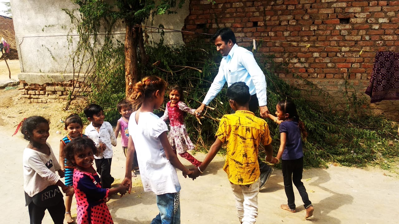 Volunteer playing a circle game with children in village lane