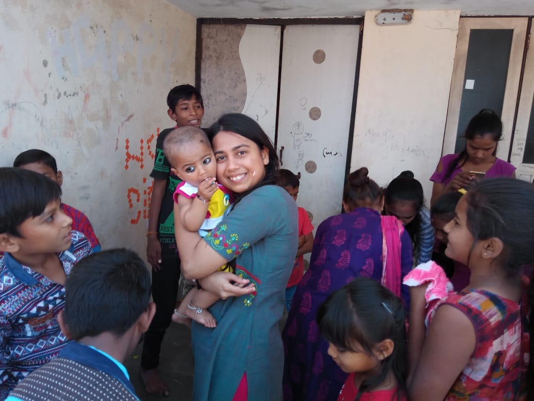Volunteer holding a baby among a larger group of children