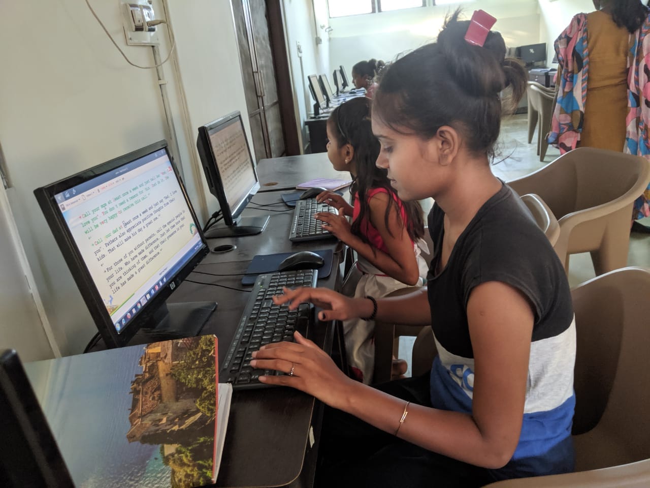 Volunteer working alongside children at desktop computers