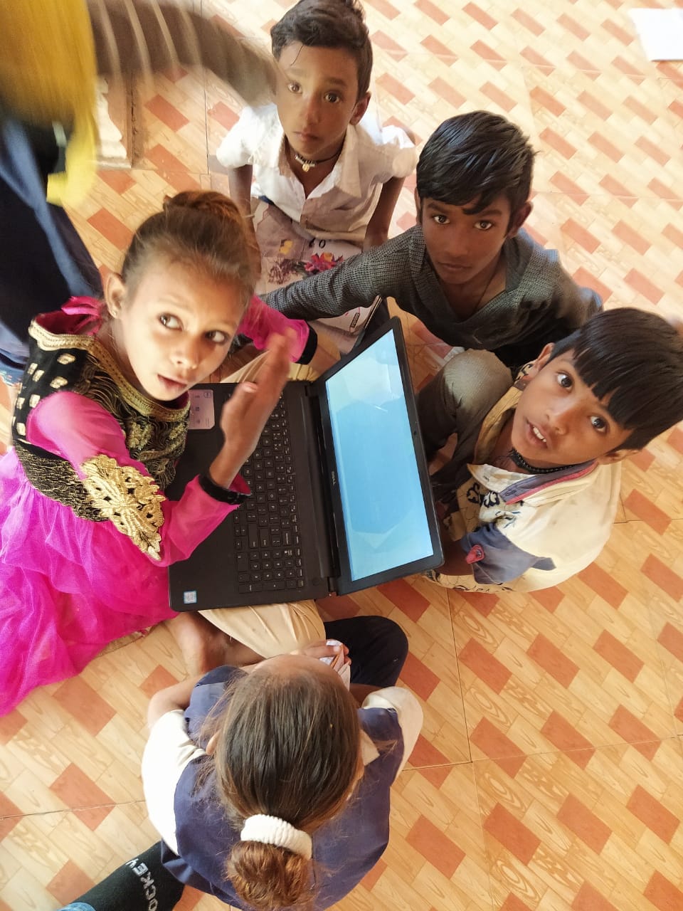 Children gathered around a laptop, learning together