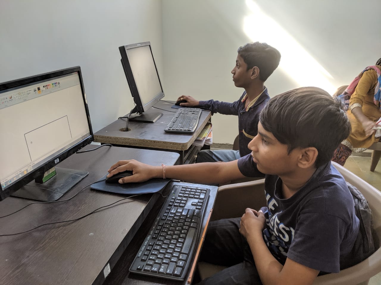 Two boys independently using desktop computers