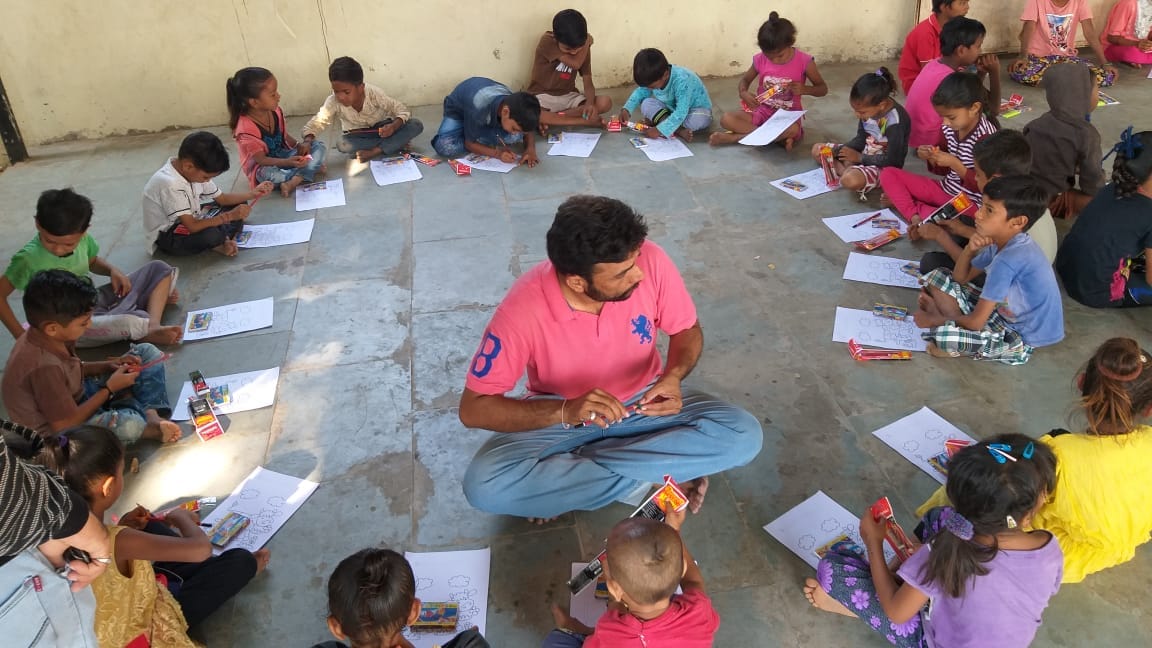 Large group of children drawing/colouring around a volunteer