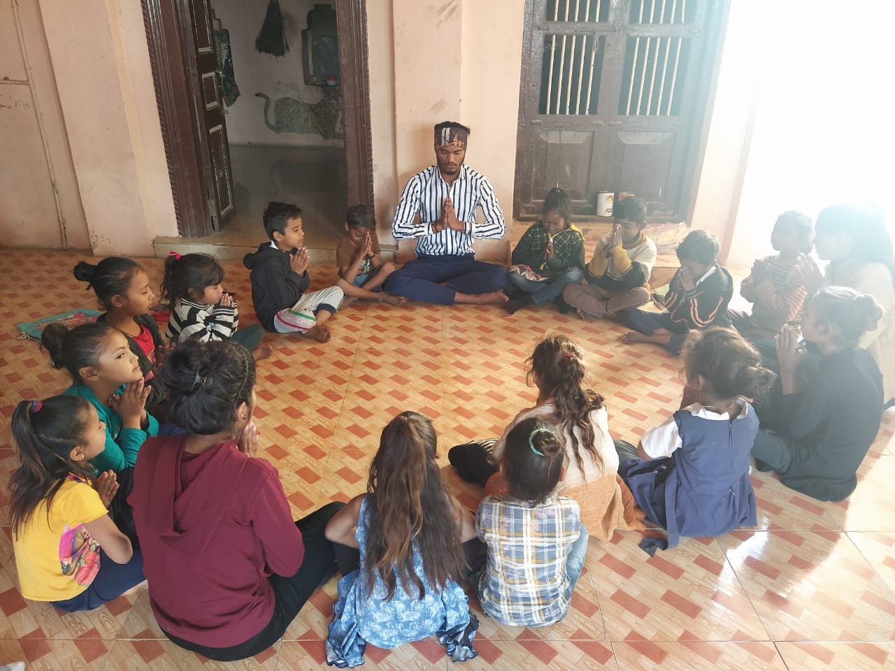 Volunteer leading children in a circle with a reflective/prayer activity