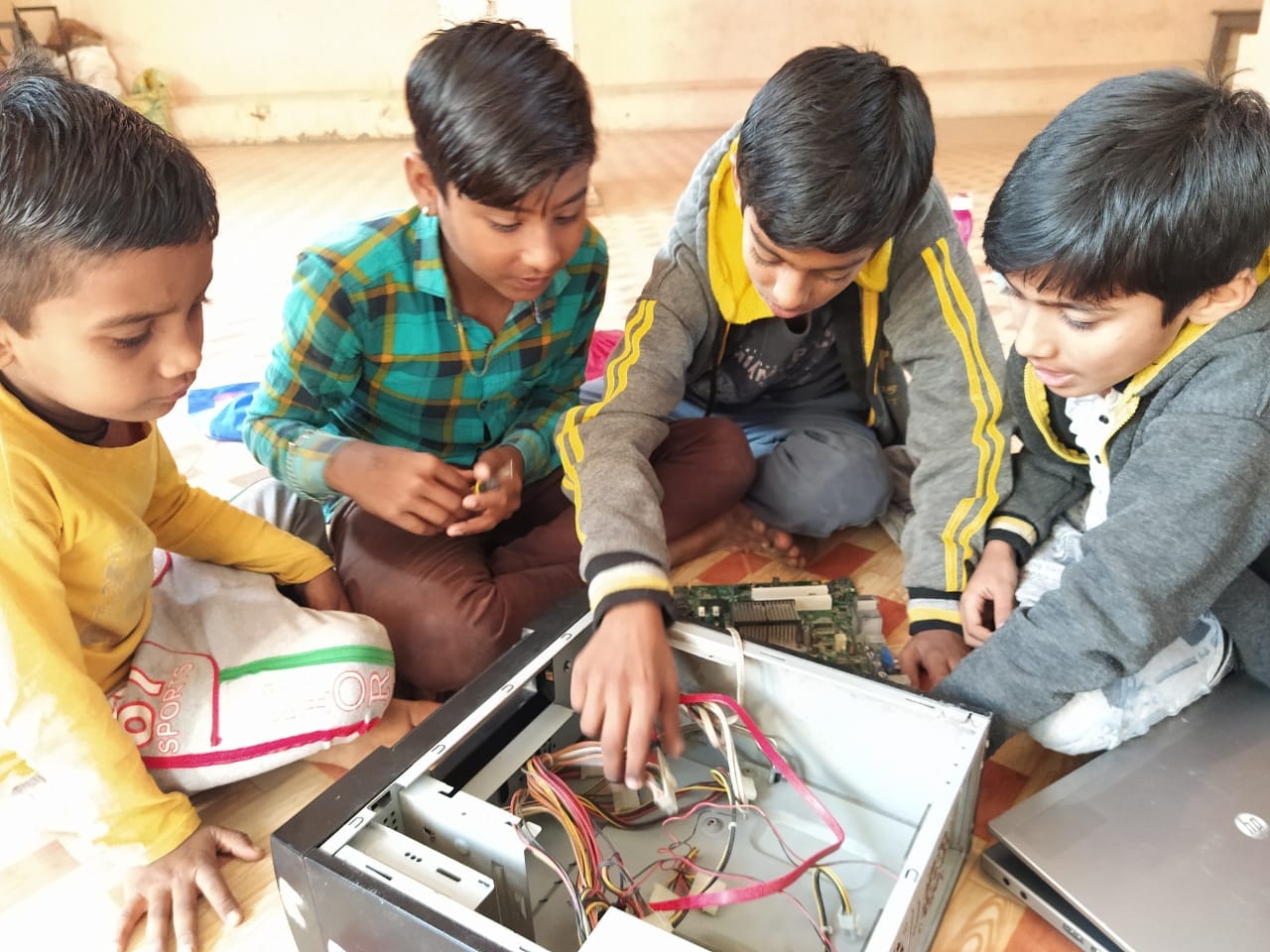 Group of children examining an opened computer together