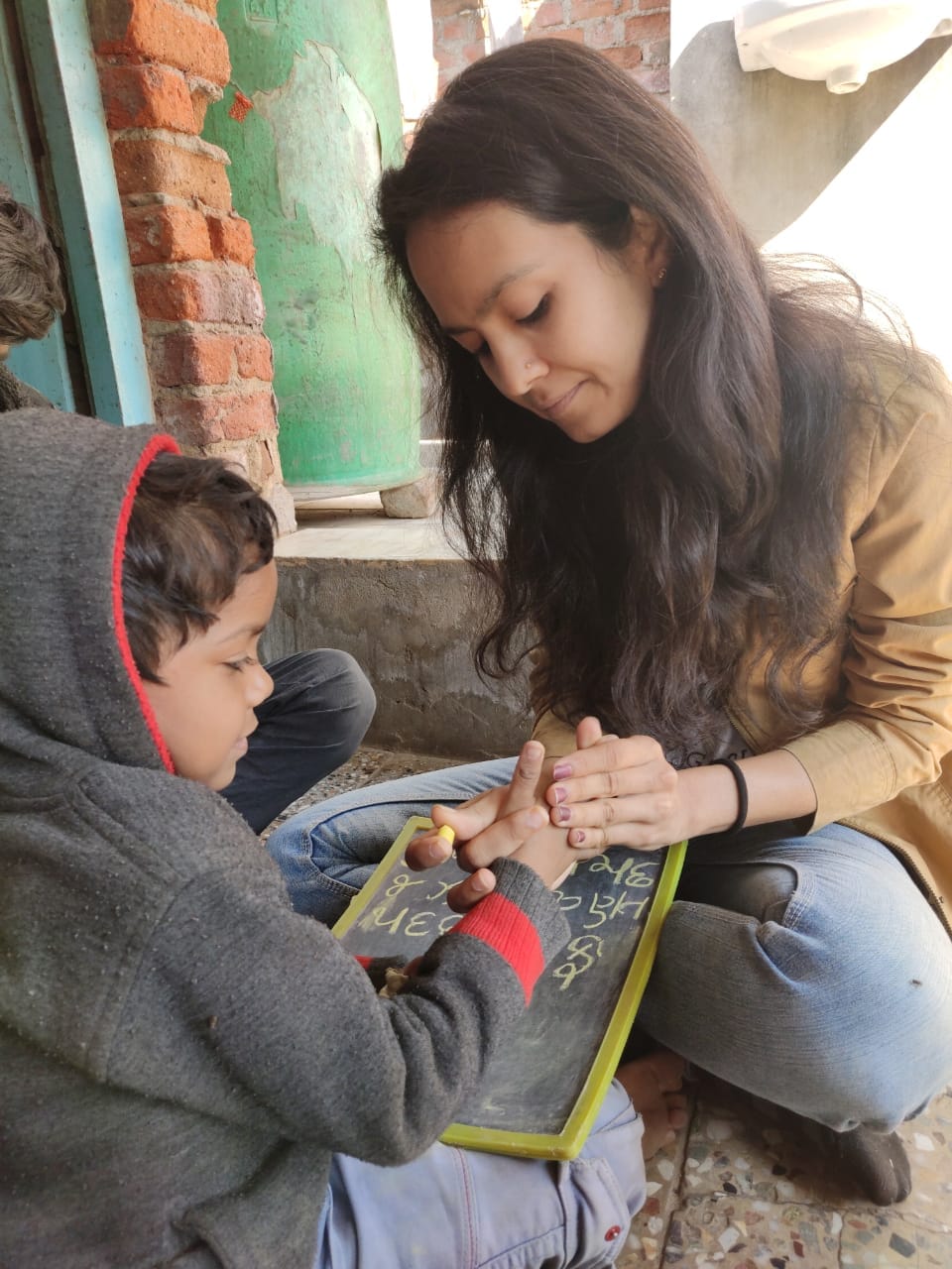 Volunteer working one-to-one with a child on a small writing board
