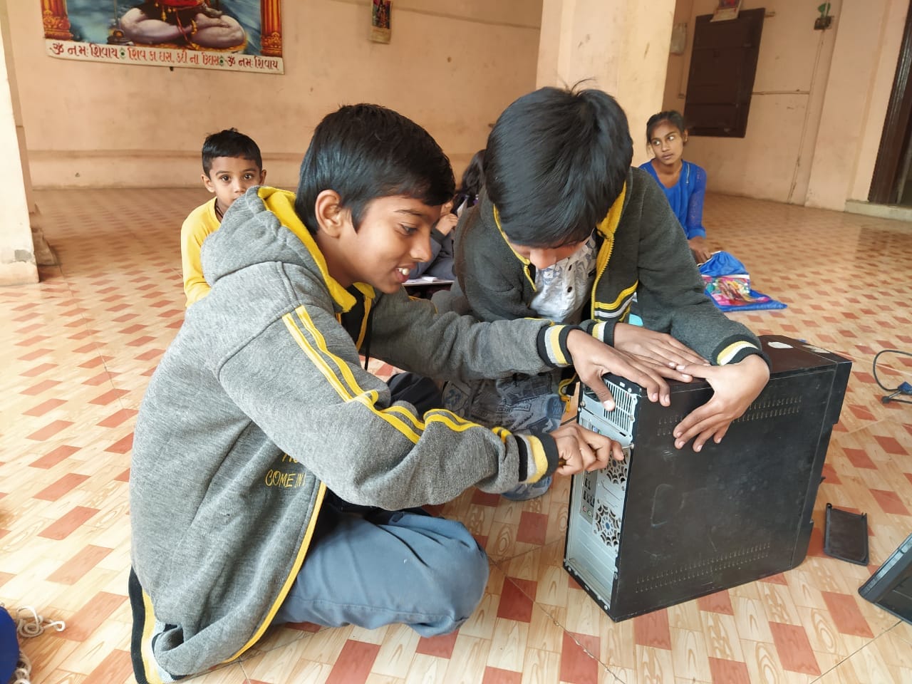 Two boys examine the components inside an open desktop computer.